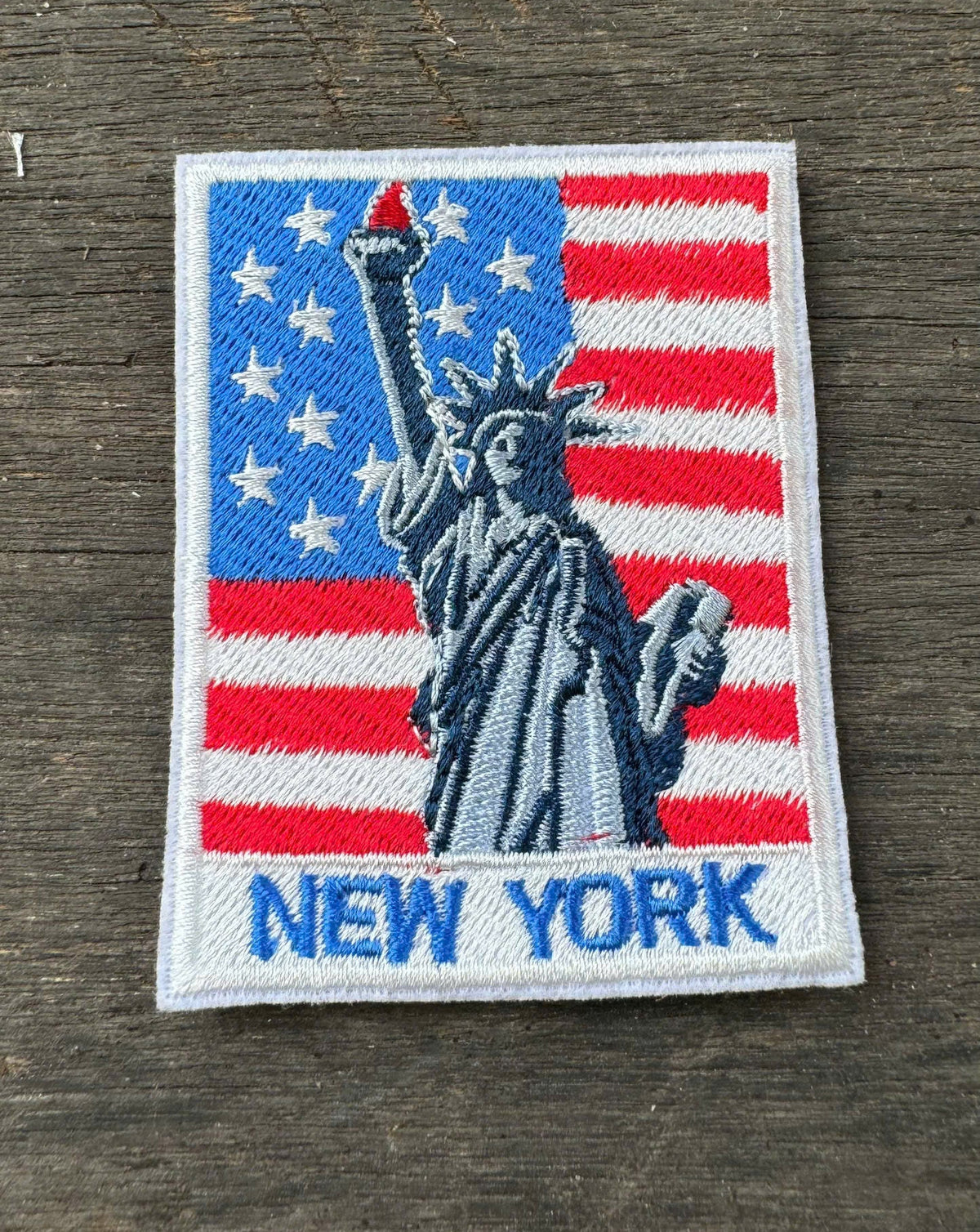 Embroidered patch with Statue of Liberty and American flag design on a wooden surface