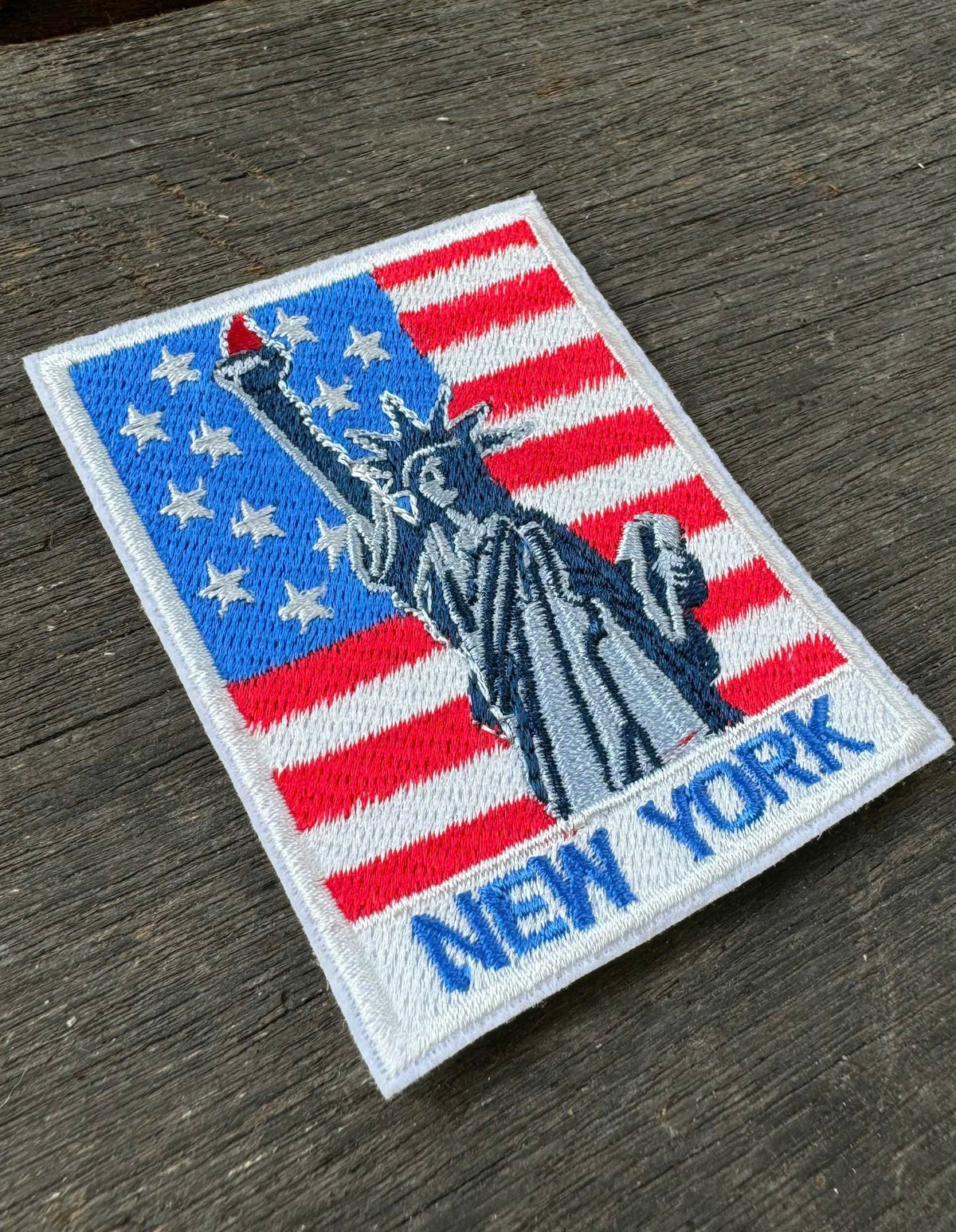 Embroidered patch with Statue of Liberty design and 'New York' text on a wooden surface