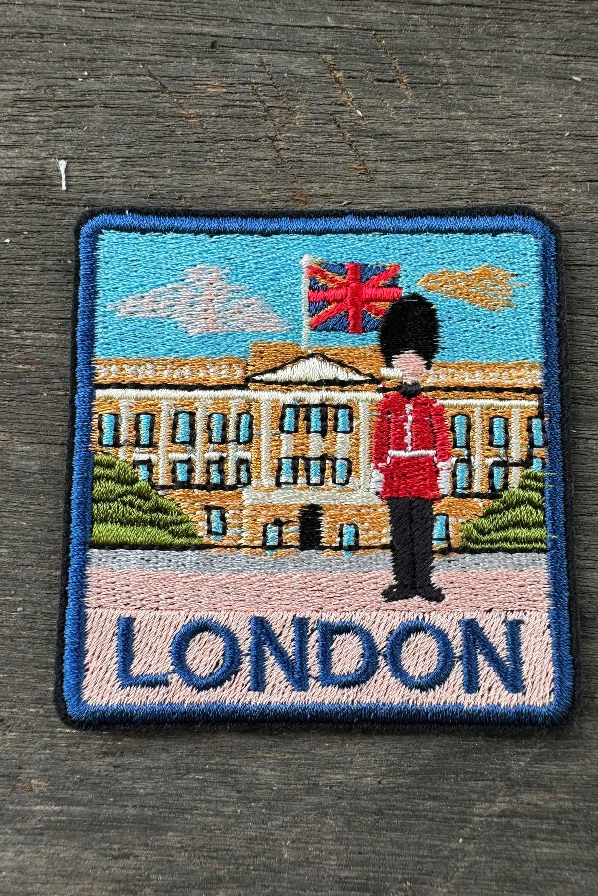 Embroidered patch with a guard, British flag, and 'London' text on a wooden surface