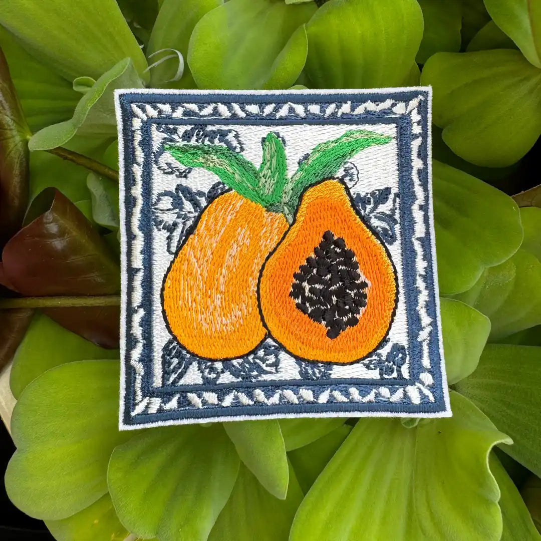 Embroidered patch of two vibrant papayas with tropical leaf border