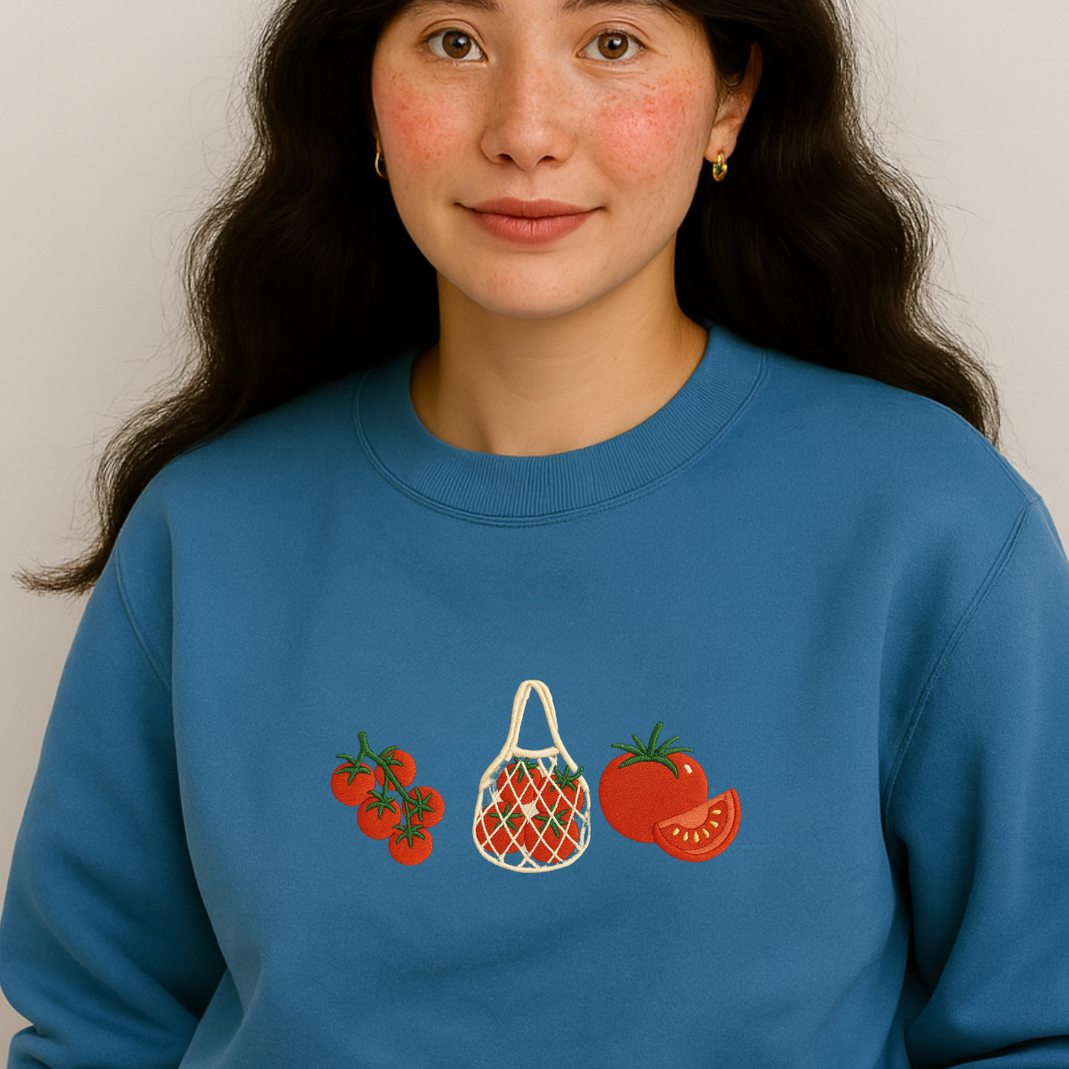Person wearing a blue sweatshirt with tomato and bag designs.