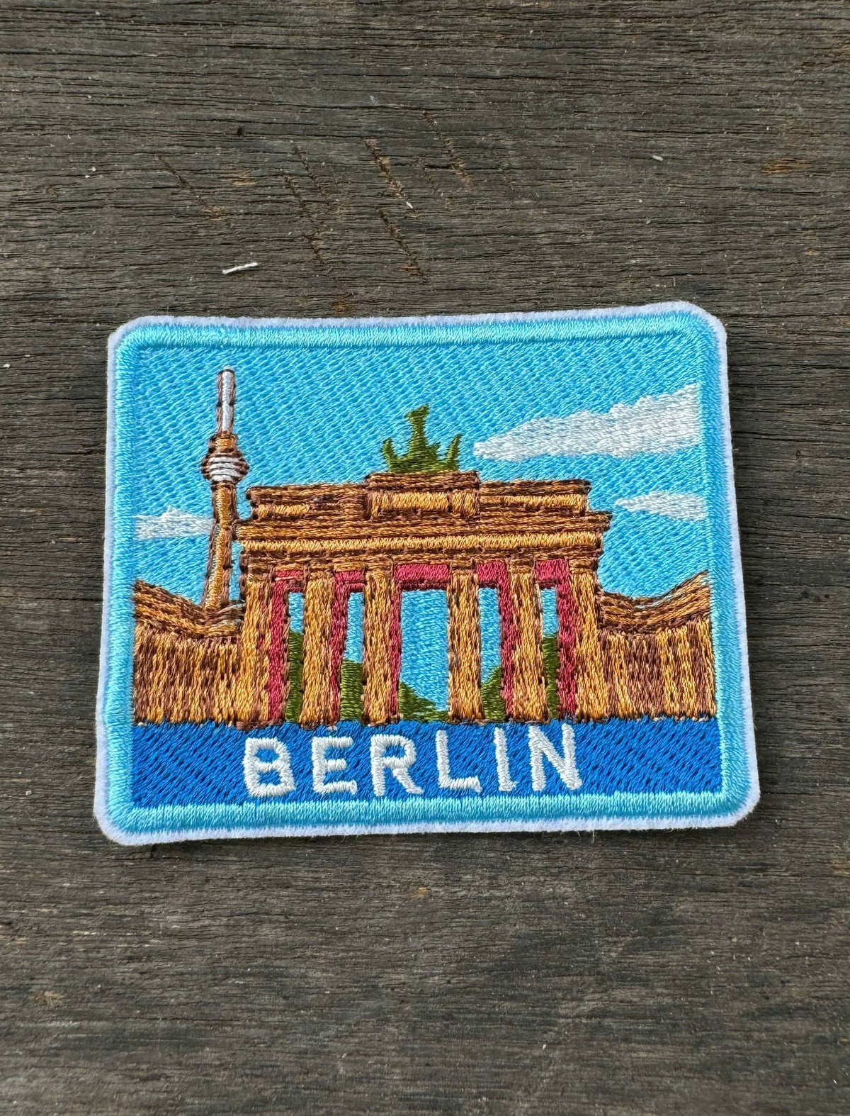 Embroidered patch of the Brandenburg Gate with 'BERLIN' text on a wooden surface