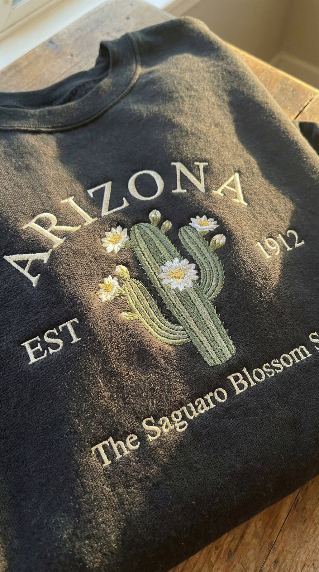 Charcoal black sweatshirt with detailed Saguaro cactus and white blossom embroidery reading Arizona EST 1912 The Saguaro Blossom State