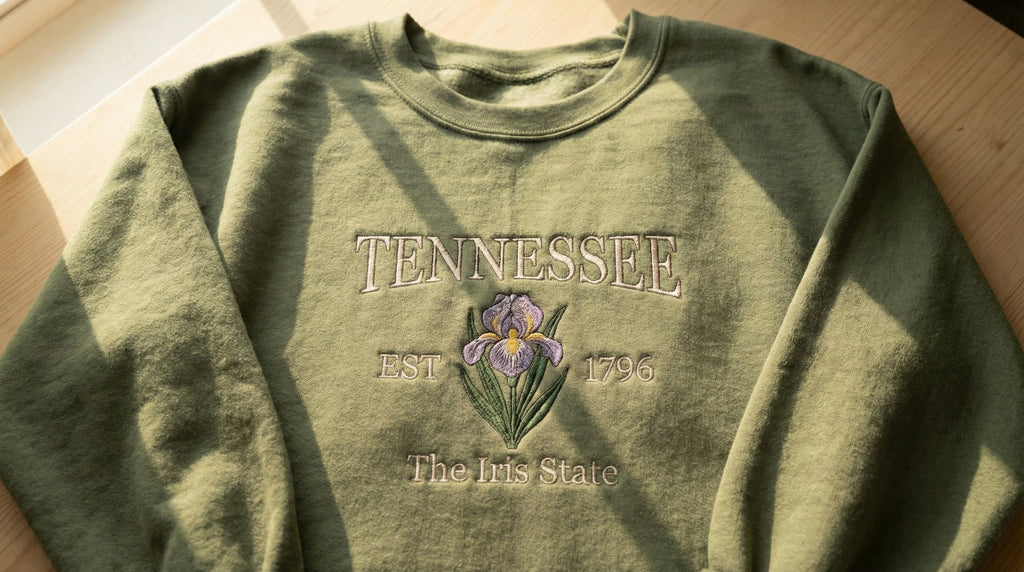 Olive green folded sweatshirt with detailed purple Iris flower embroidery reading Tennessee EST 1796 The Iris State