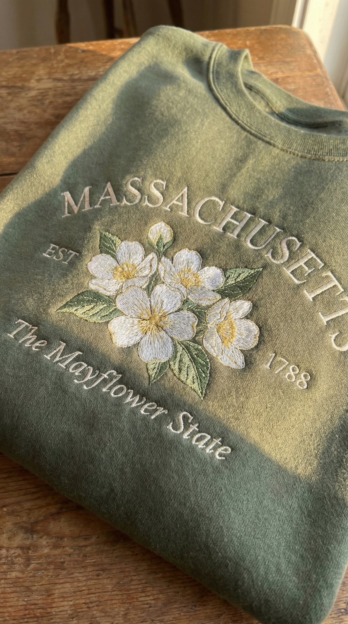 Olive green sweatshirt with detailed white Mayflower flower embroidery reading Massachusetts EST 1788 The Mayflower State