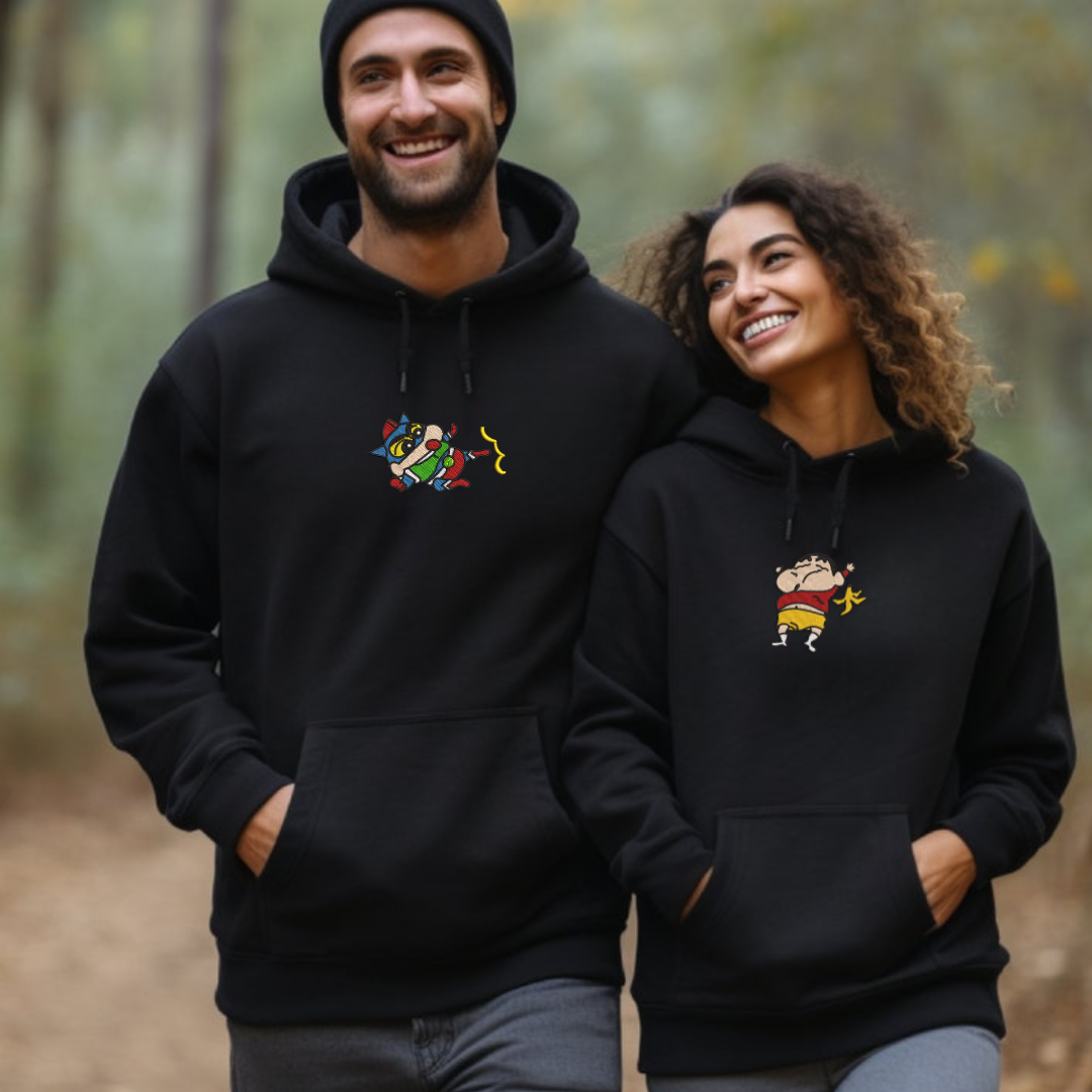 Black embroidered hoodie with colorful ShinChan design, couple modeling on forest background