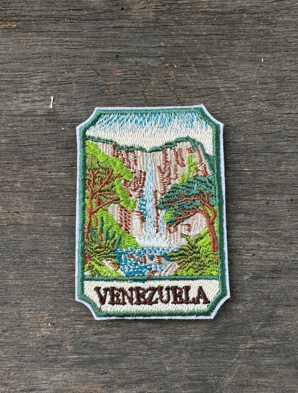 Embroidered patch of Venezuela with a waterfall design on a wooden surface