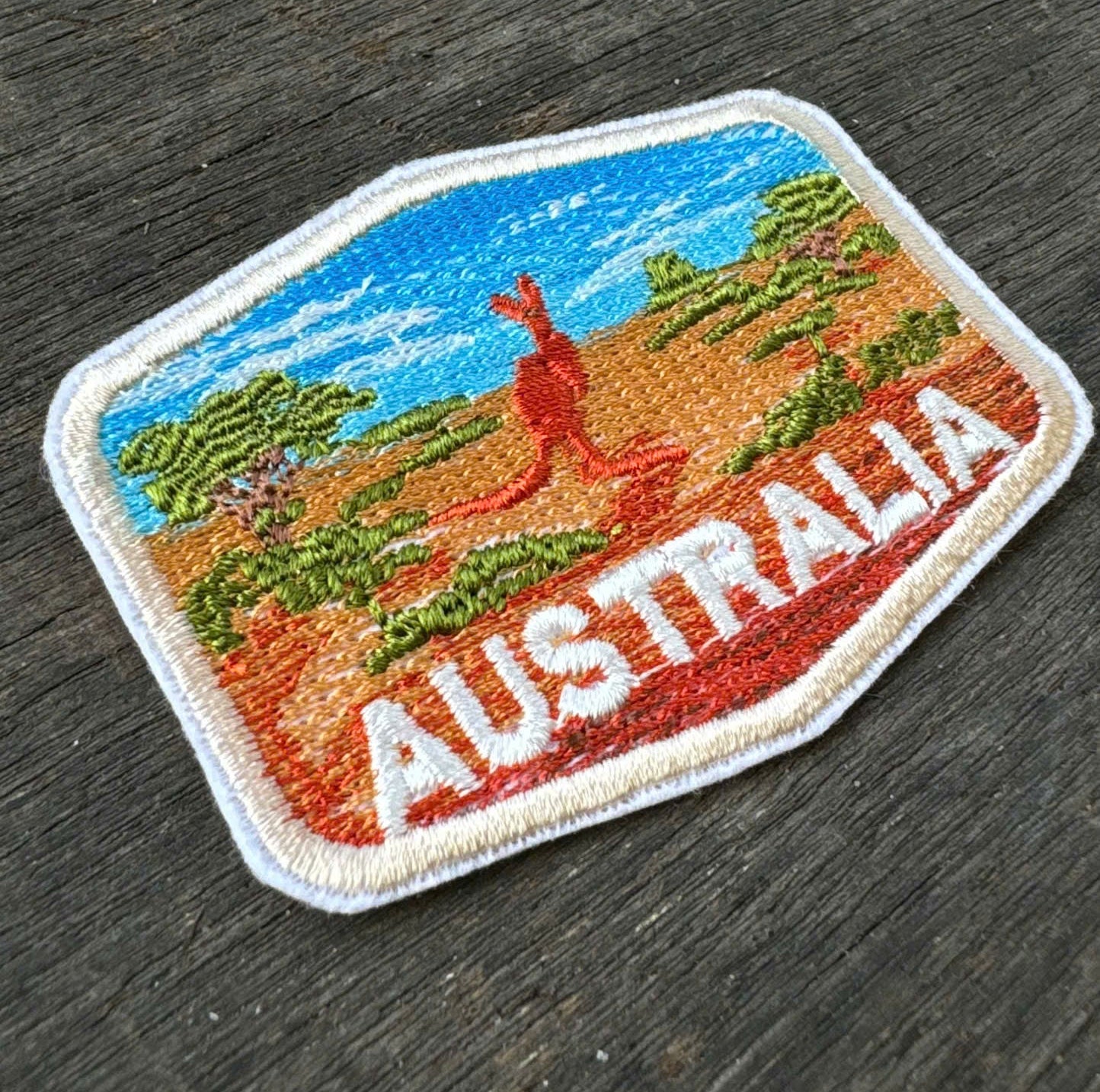 Embroidered patch of Australia with a kangaroo on a wooden surface