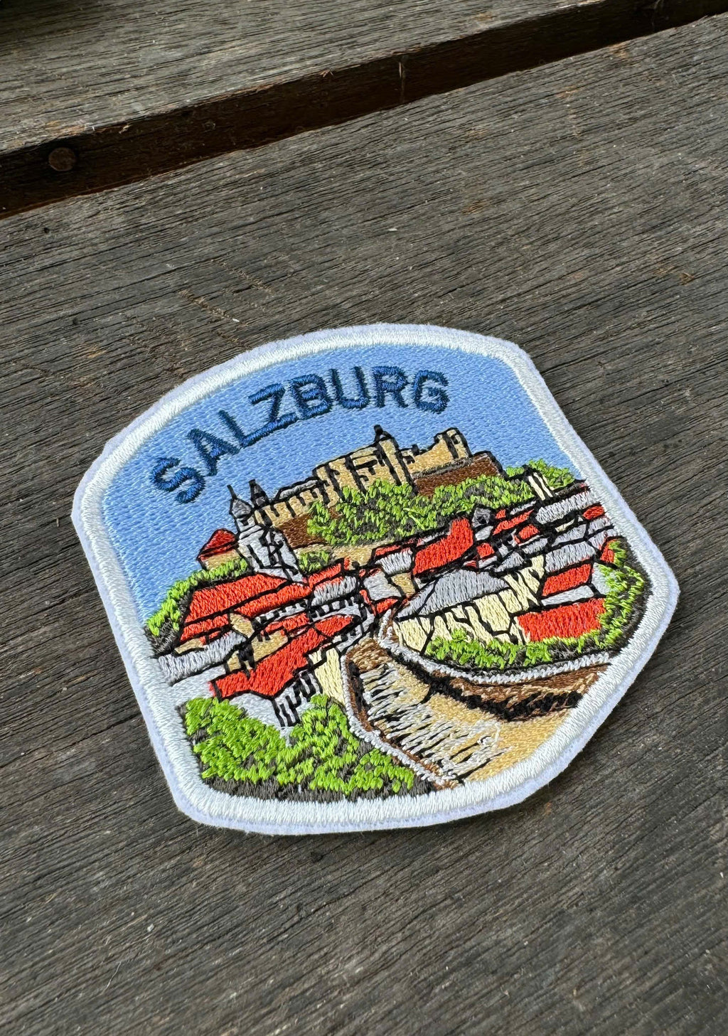 Embroidered patch of Salzburg on a wooden surface