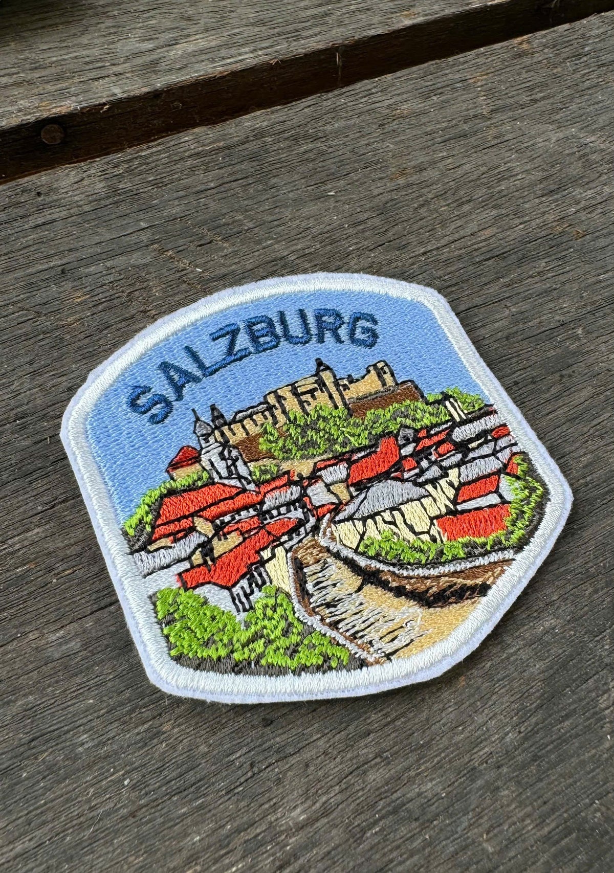 Embroidered patch of Salzburg on a wooden surface