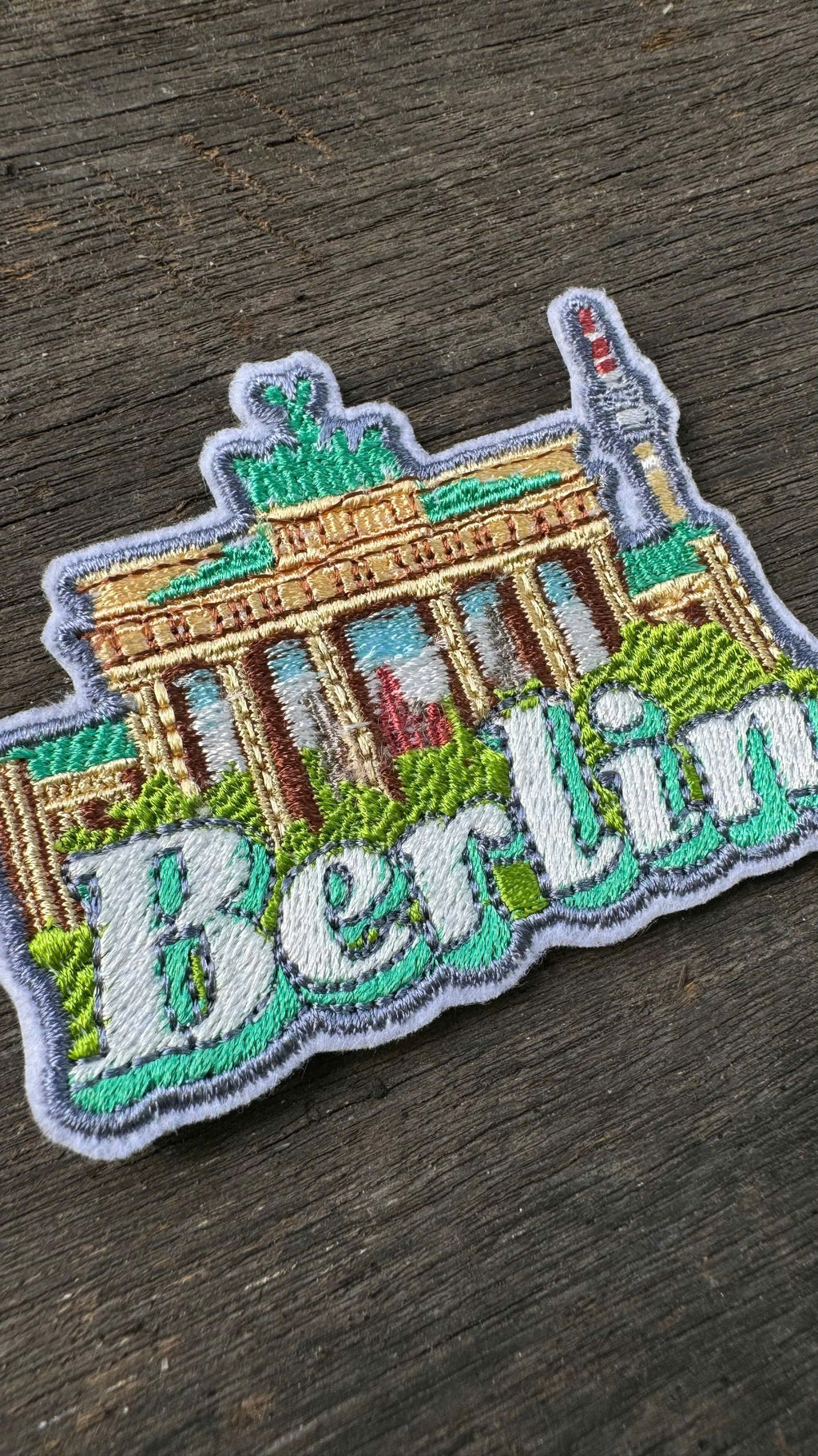 Embroidered patch of the Brandenburg Gate with 'Berlin' text on a wooden surface