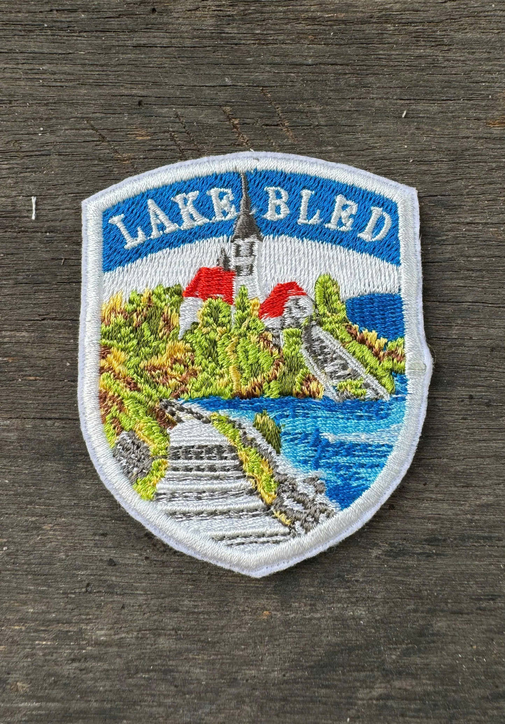 Embroidered patch of Lake Bled on a wooden surface