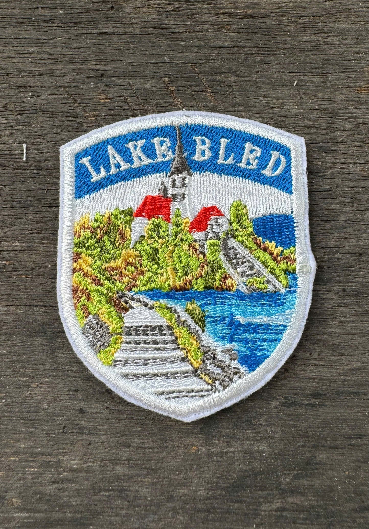 Embroidered patch of Lake Bled on a wooden surface