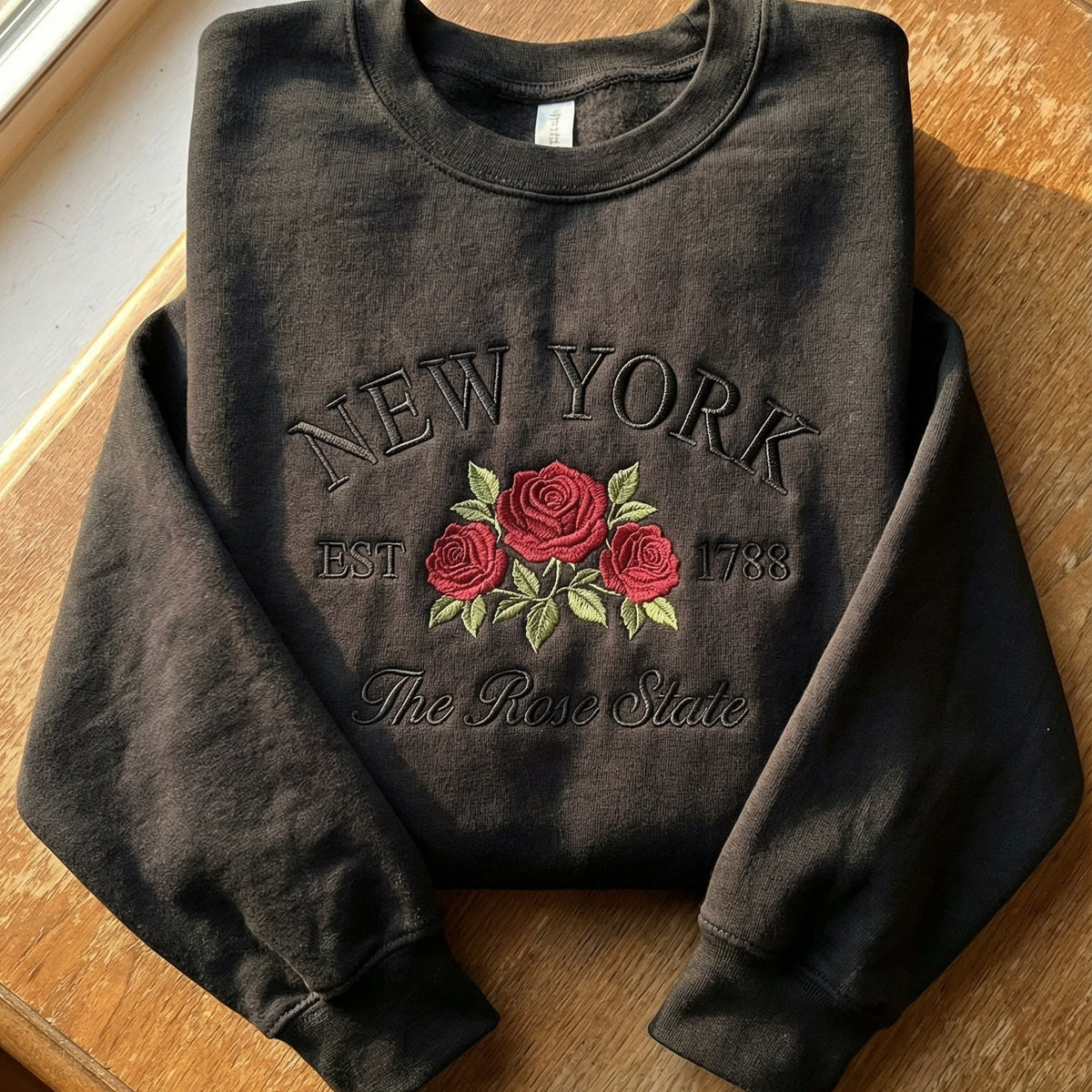 Black folded sweatshirt with detailed red Rose flower embroidery reading New York EST 1788 The Rose State
