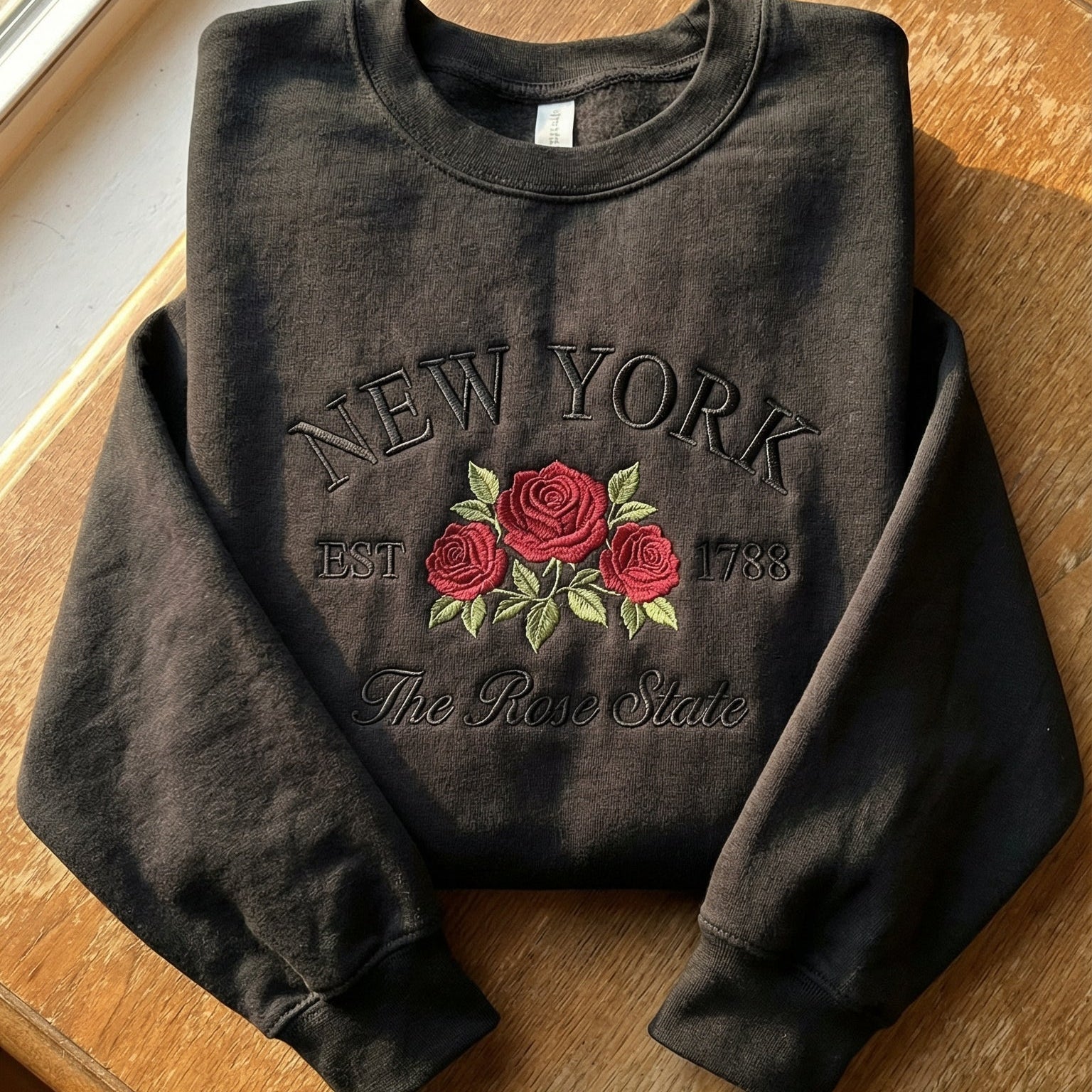 Black folded sweatshirt with detailed red Rose flower embroidery reading New York EST 1788 The Rose State