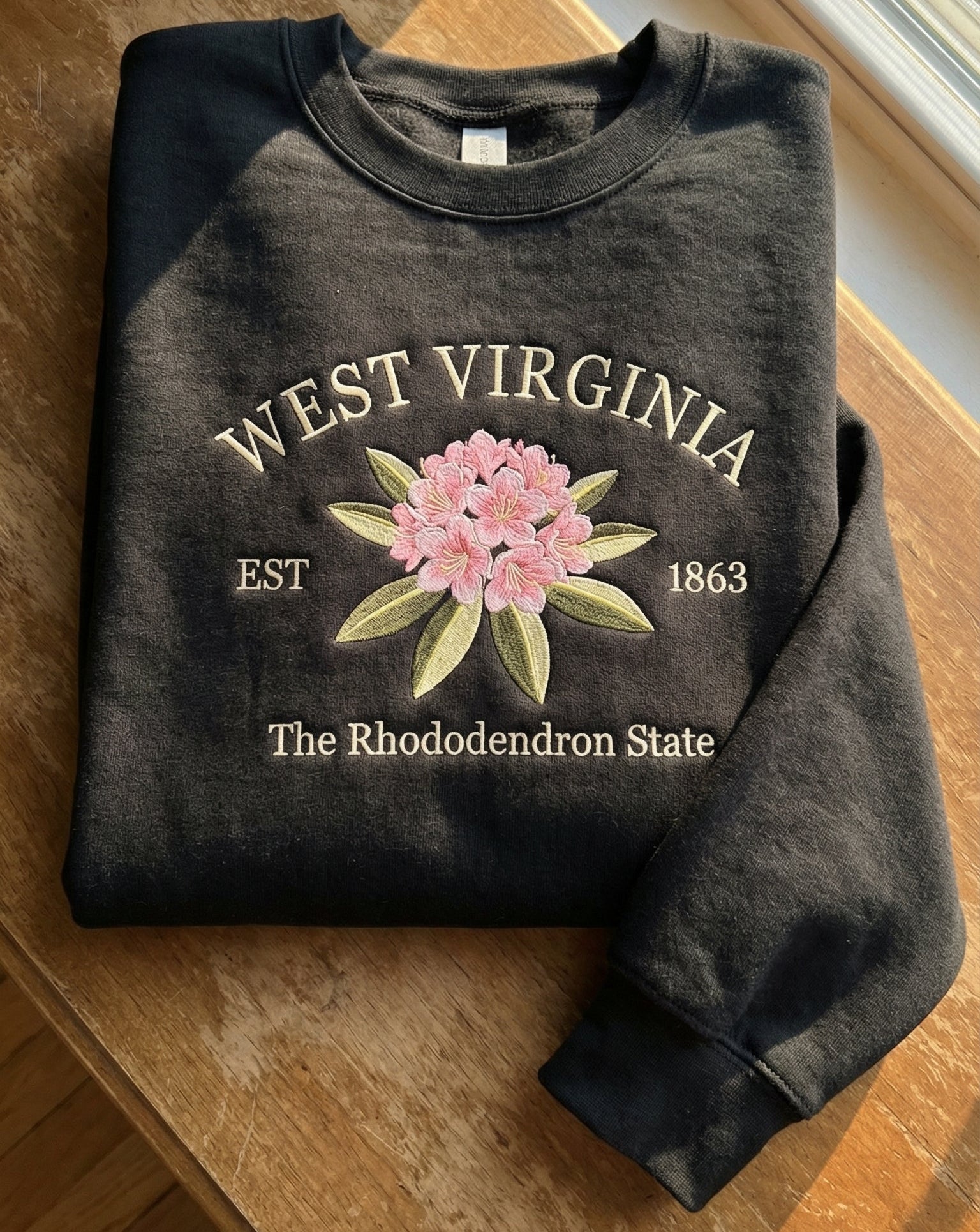 Charcoal black sweatshirt with detailed pink Rhododendron flower embroidery reading West Virginia EST 1863 The Rhododendron State
