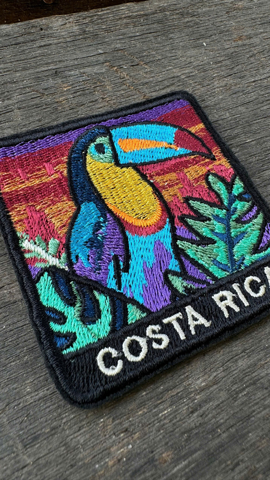 Colorful patch with a toucan design and 'Costa Rica' text on a wooden surface