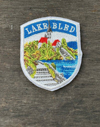 Embroidered patch of Lake Bled on a wooden surface
