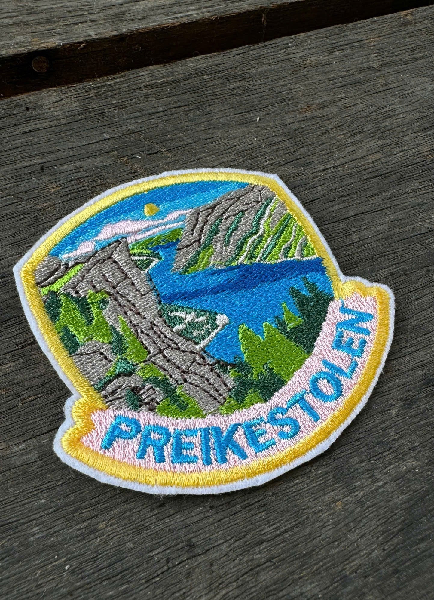 Embroidered patch of Preikestolen mountain on a wooden surface
