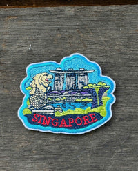 Embroidered patch of Singapore with a building design on a wooden surface