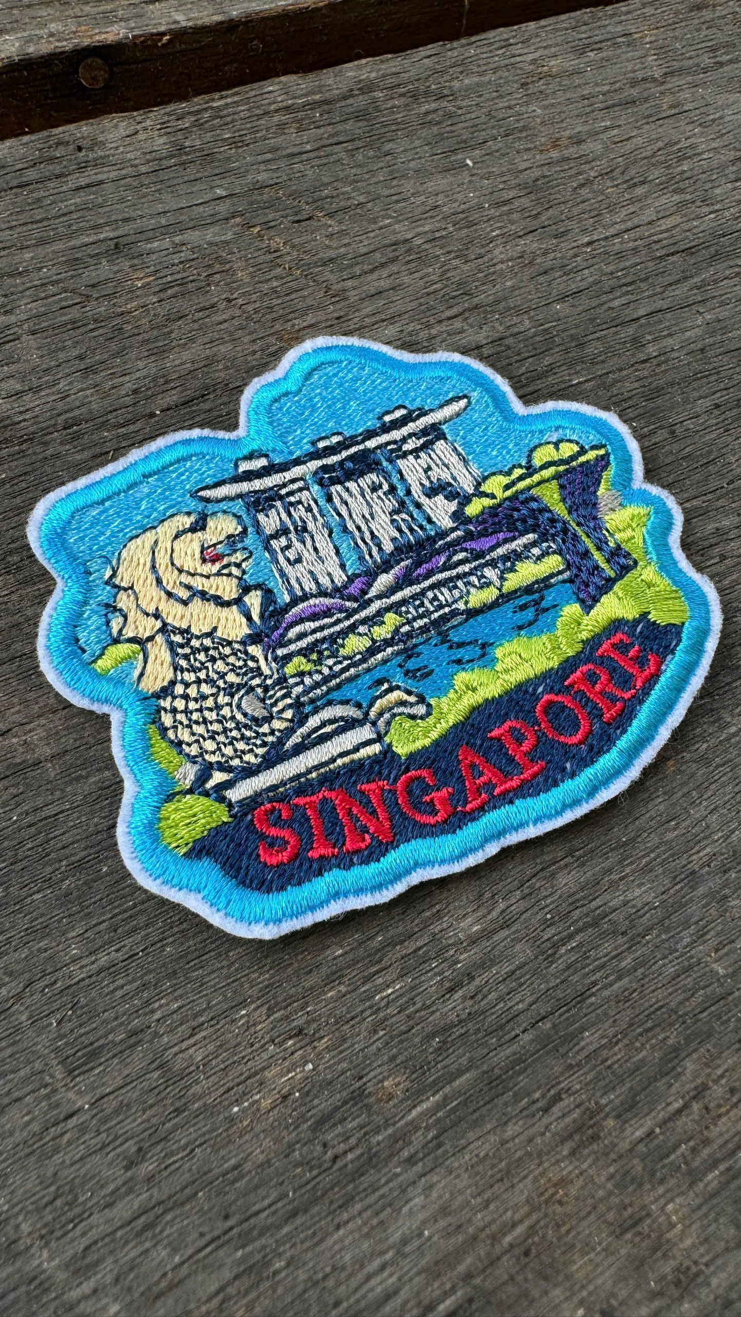 Embroidered patch of Singapore with the Marina Bay Sands on a wooden surface