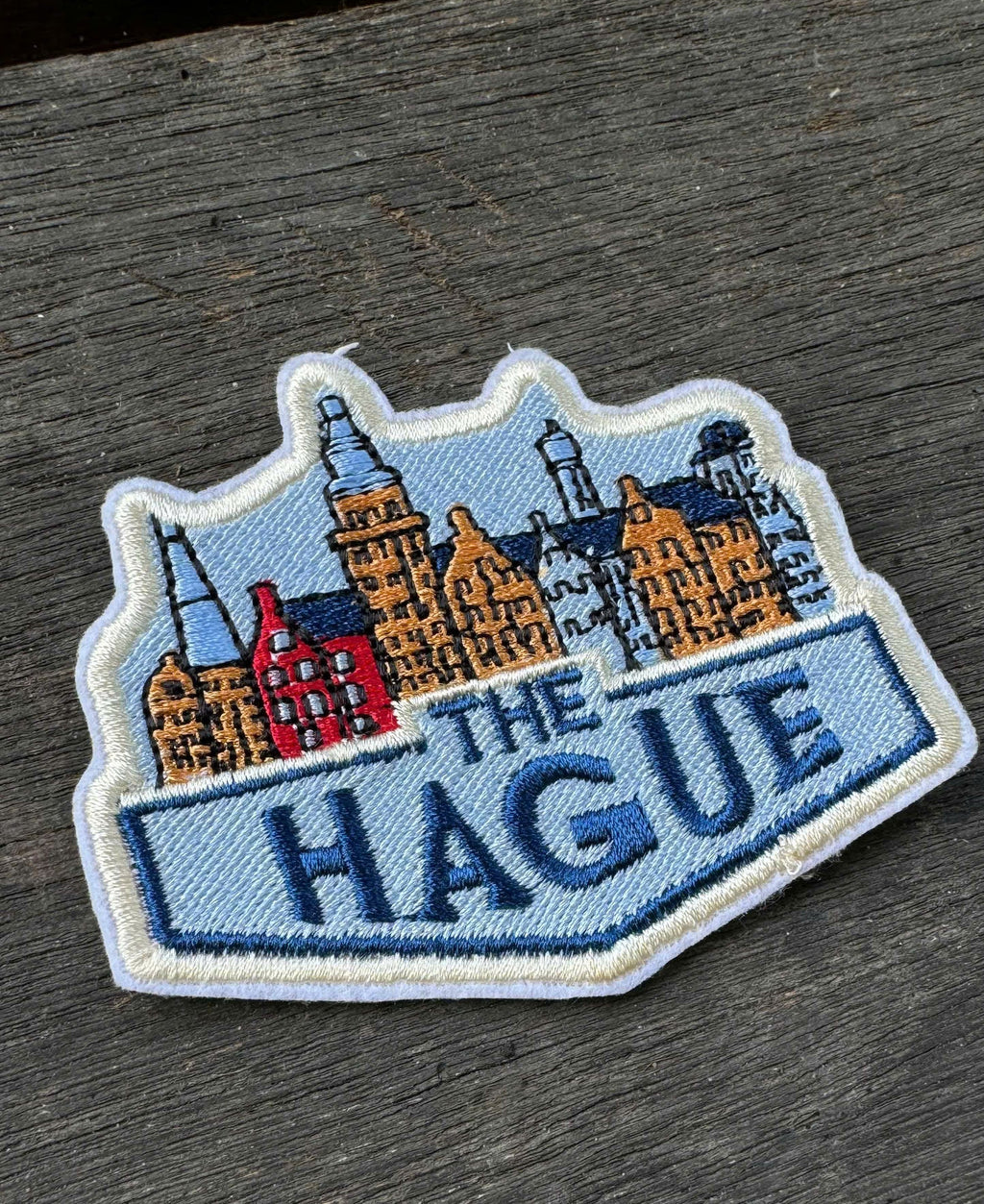 Embroidered patch of 'The Hague' with cityscape design on a wooden surface