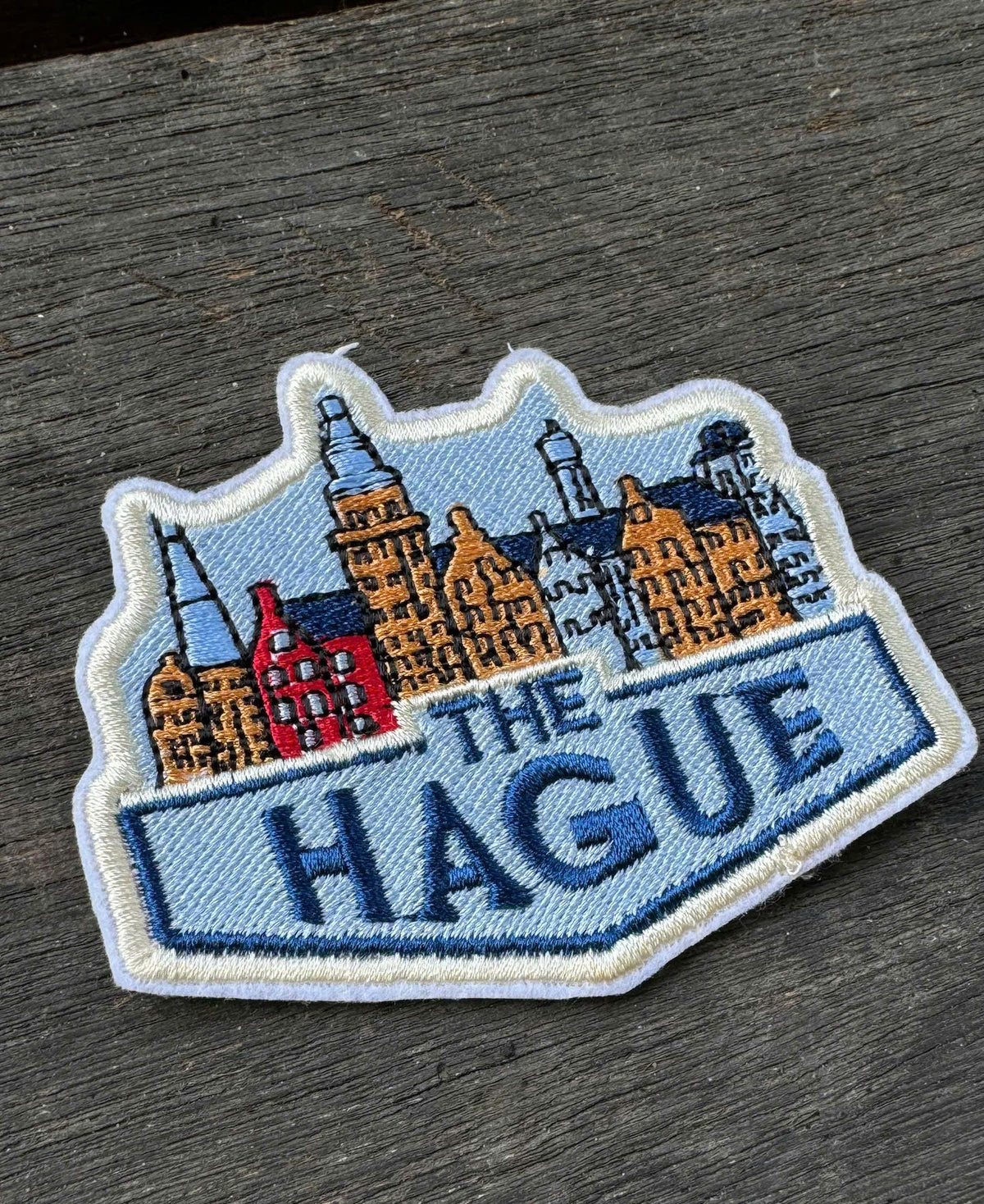 Embroidered patch of 'The Hague' with cityscape design on a wooden surface