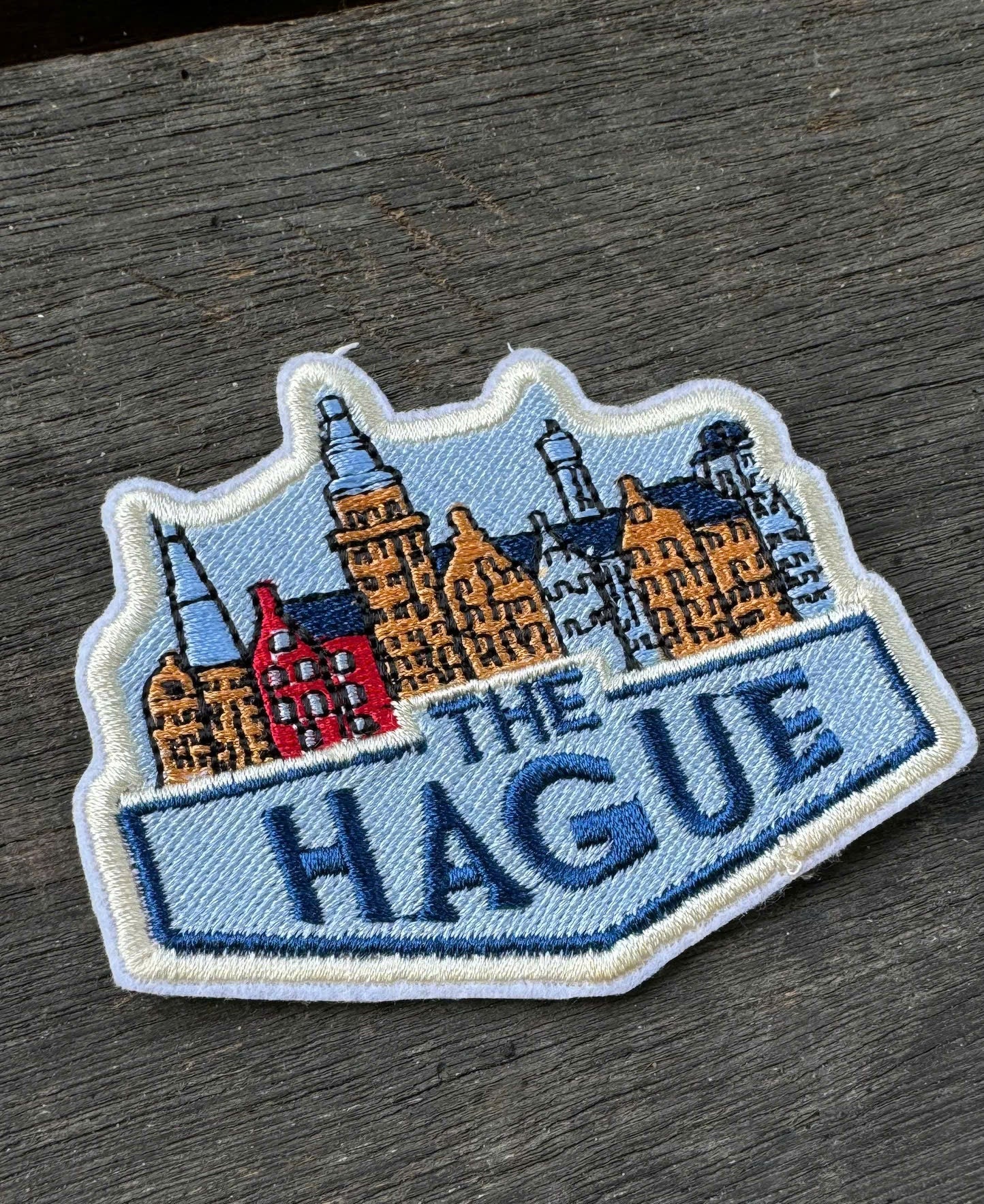 Embroidered patch of 'The Hague' with cityscape design on a wooden surface