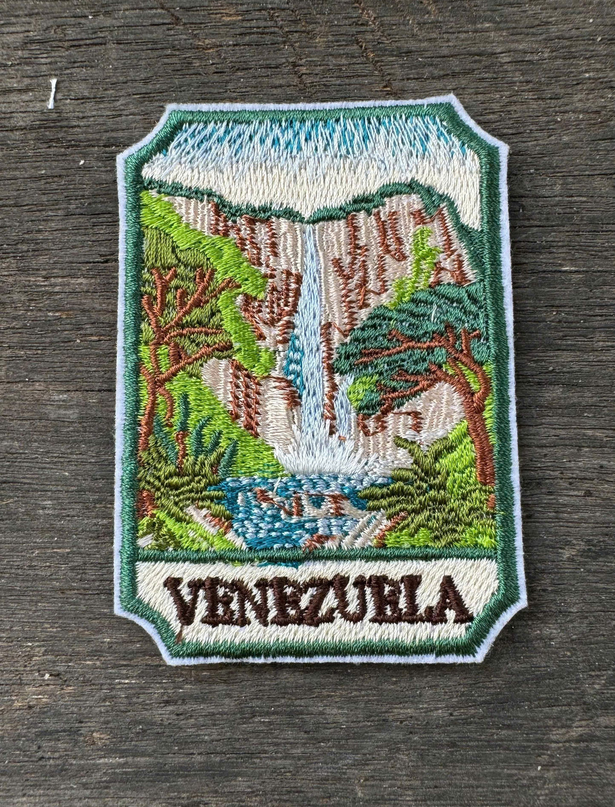 Embroidered patch of Venezuela with a waterfall design on a wooden surface