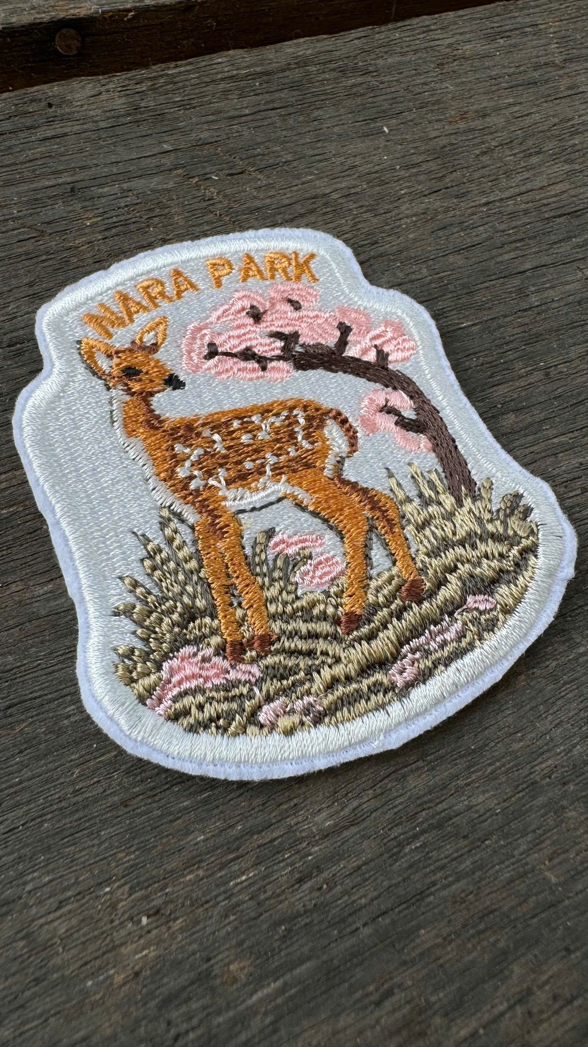 Embroidered patch of a deer in Nara Park on a wooden surface
