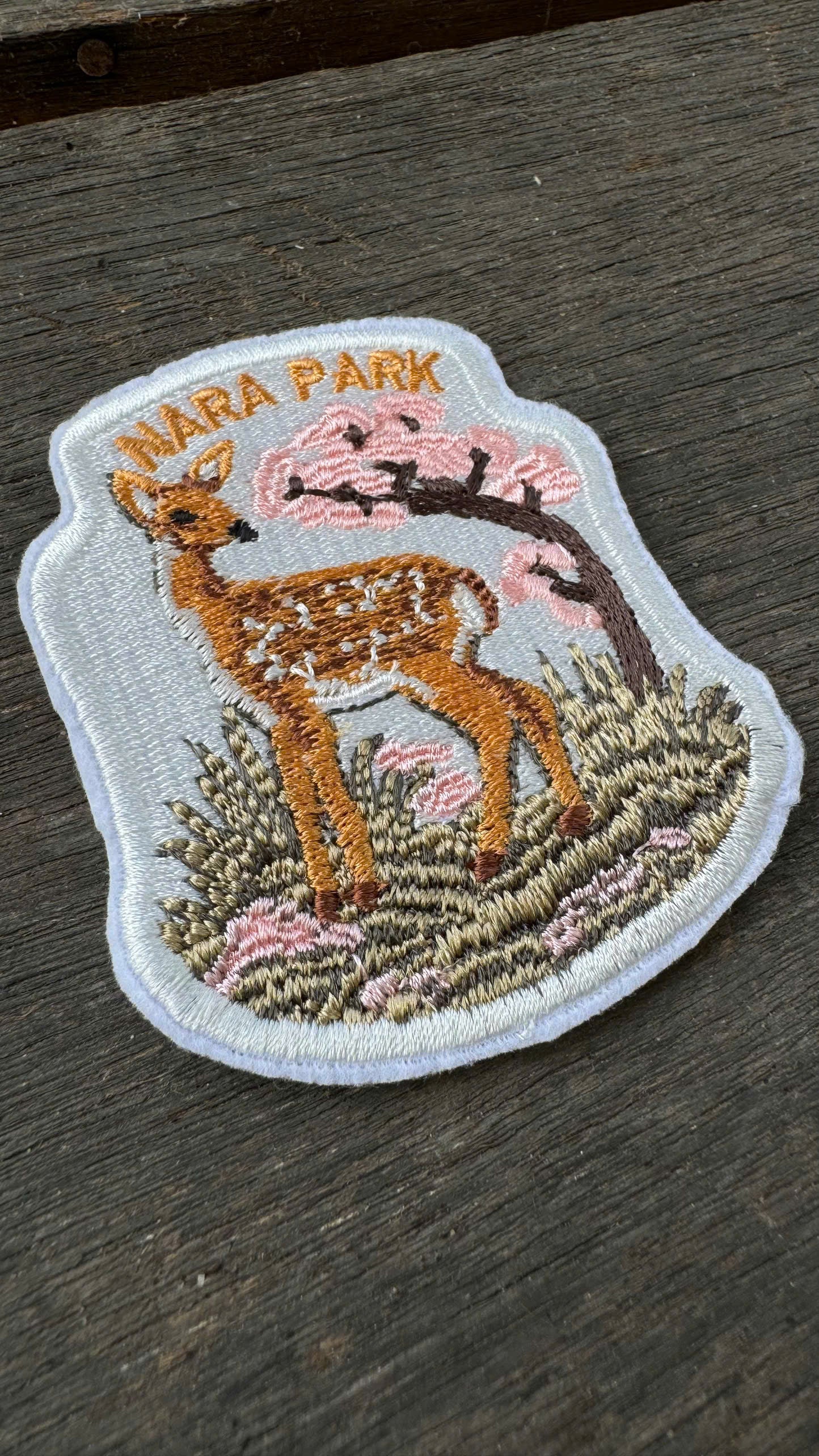 Embroidered patch of a deer in Nara Park on a wooden surface