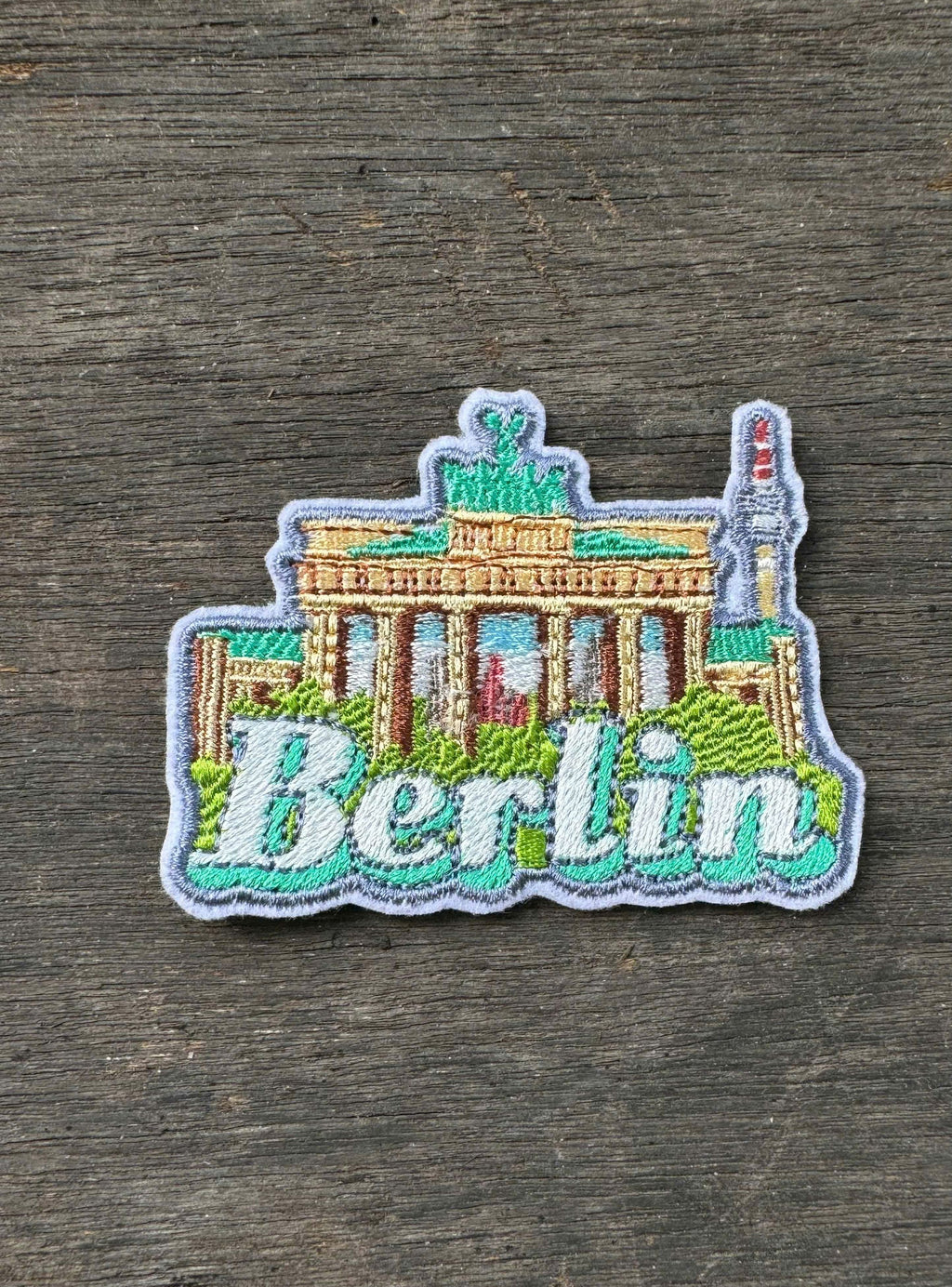 Embroidered patch of the Brandenburg Gate with 'Berlin' text on a wooden surface