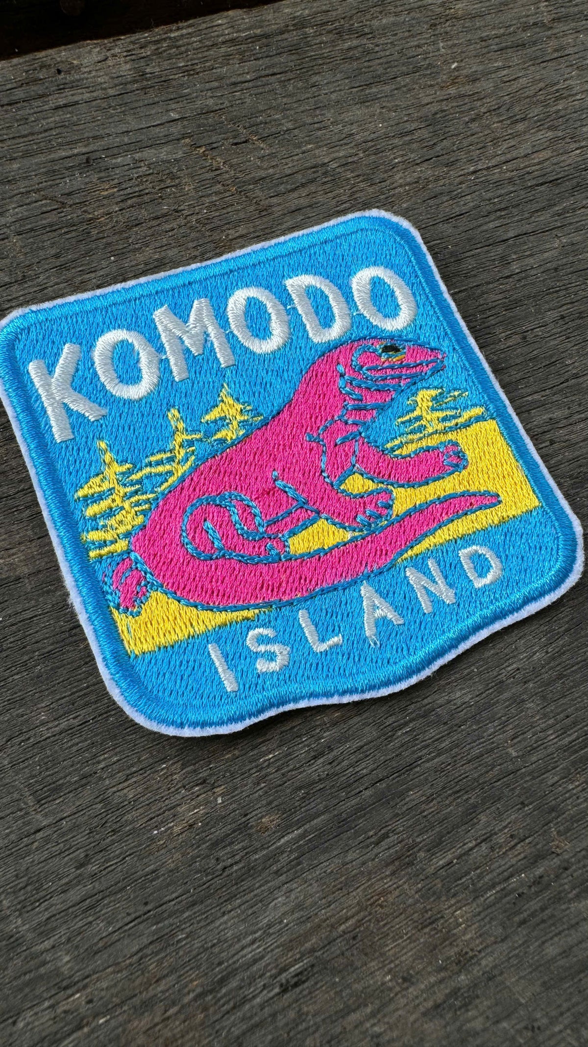 Embroidered patch with Komodo Island design on a wooden surface