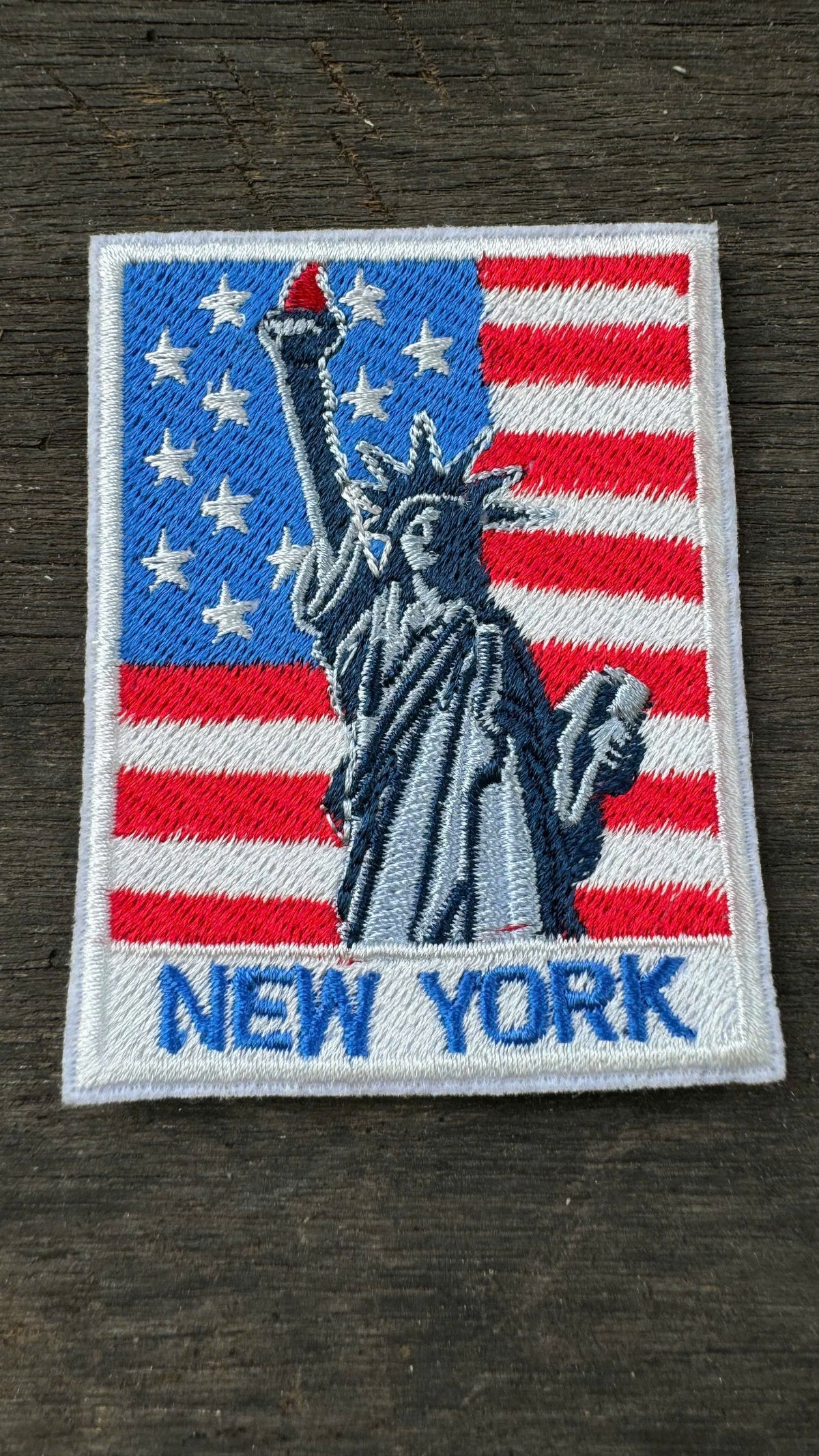 Embroidered patch with Statue of Liberty and American flag design on a wooden surface