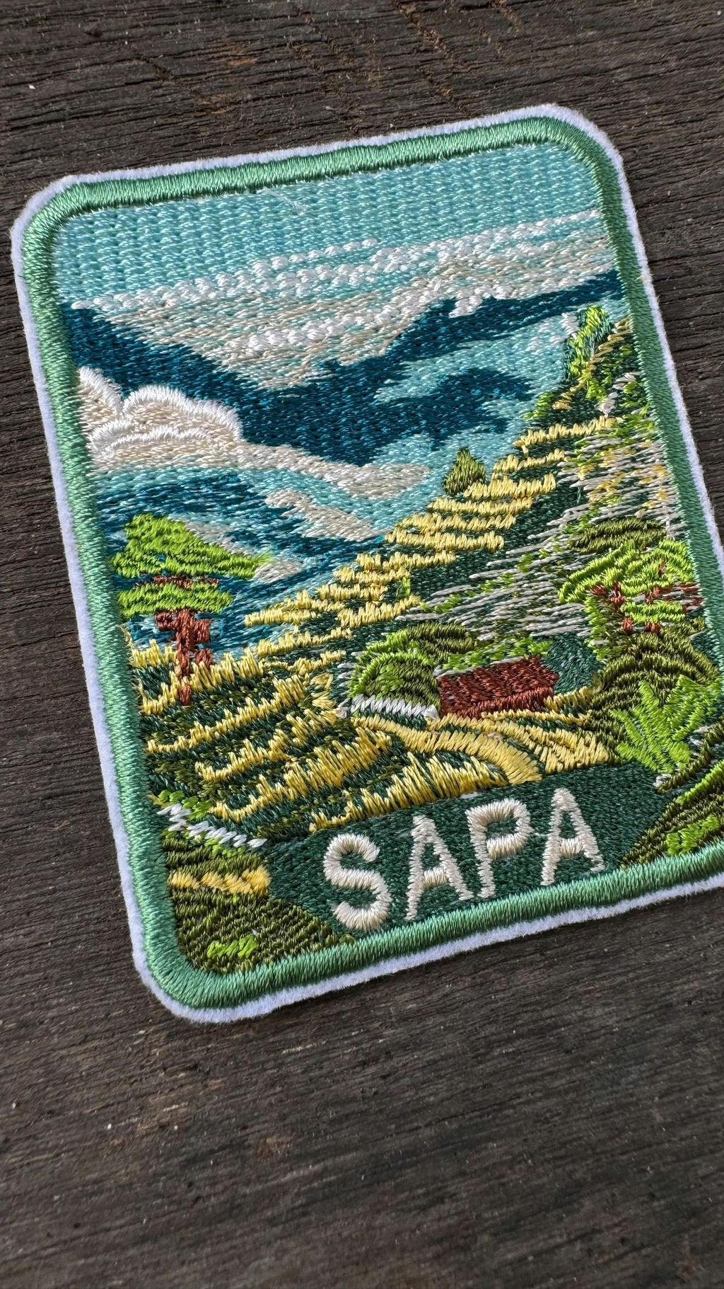 Embroidered patch with a scenic landscape and 'Sapa' text on a dark surface
