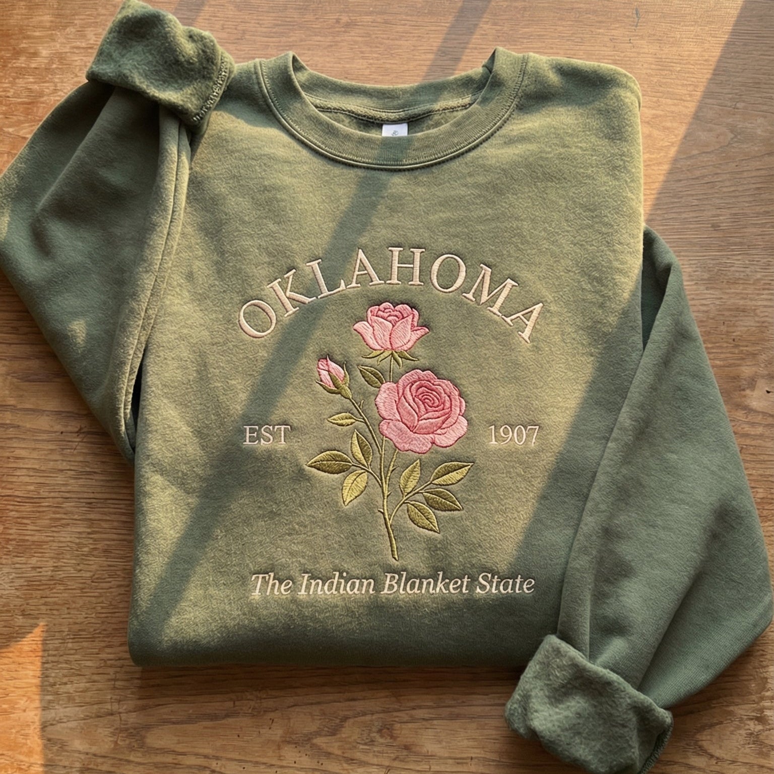 Olive green sweatshirt with detailed pink Rose flower embroidery reading Oklahoma EST 1907 The Indian Blanket State