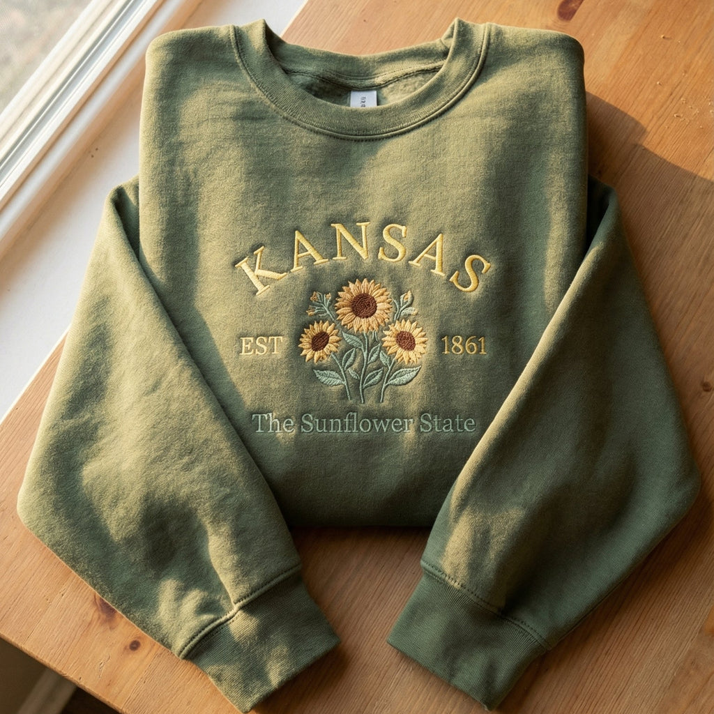Olive green sweatshirt with detailed yellow Sunflower embroidery reading Kansas EST 1861 The Sunflower State