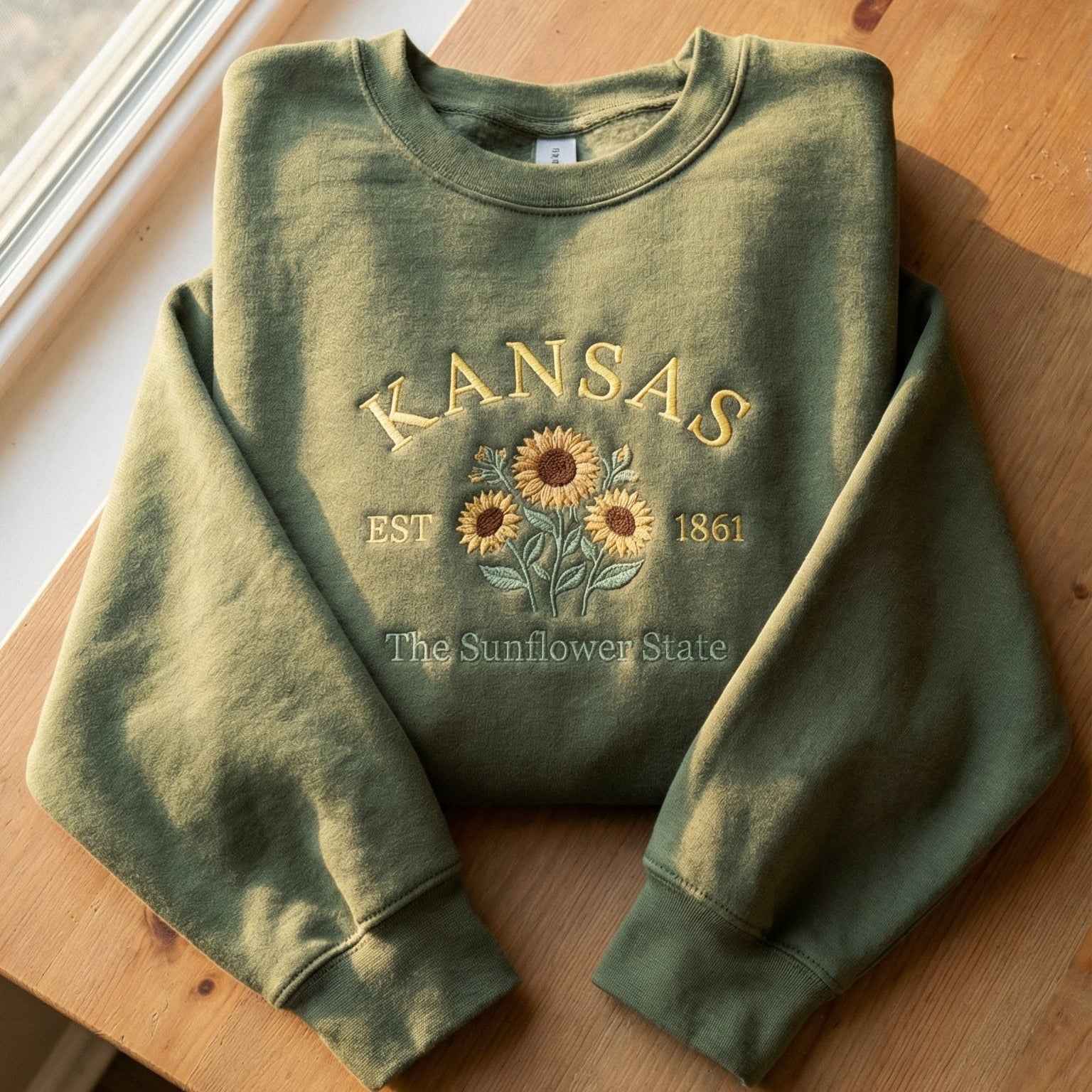 Olive green sweatshirt with detailed yellow Sunflower embroidery reading Kansas EST 1861 The Sunflower State