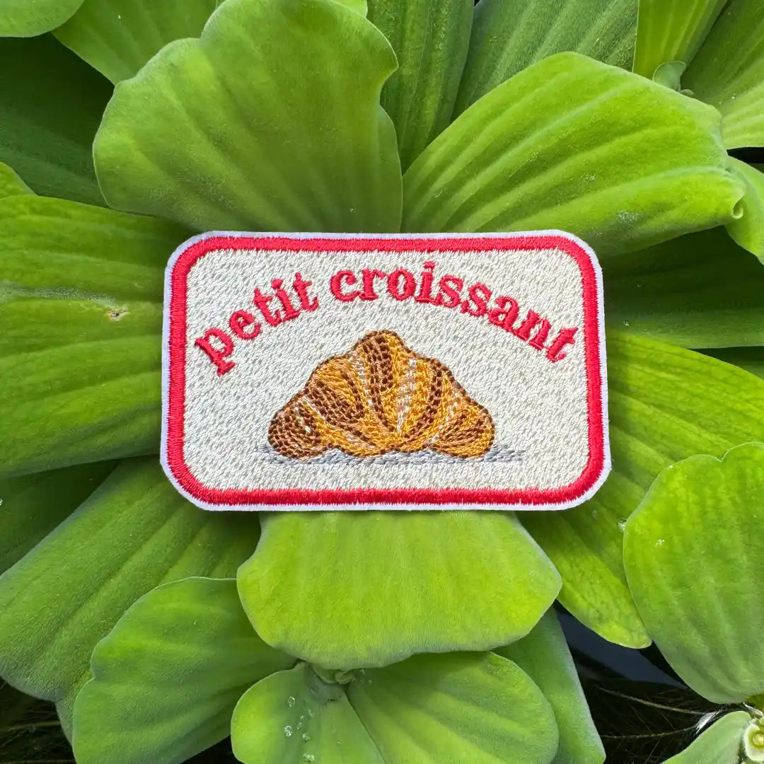 Petit croissant embroidered patch on green leaf background