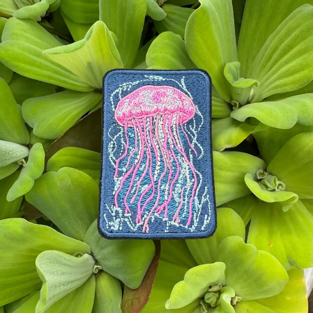 Embroidered pink jellyfish patch on green leaf background