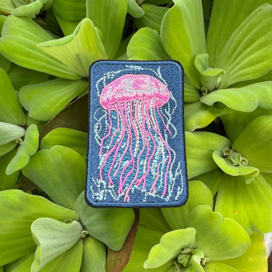 Embroidered pink jellyfish patch on green leaf background
