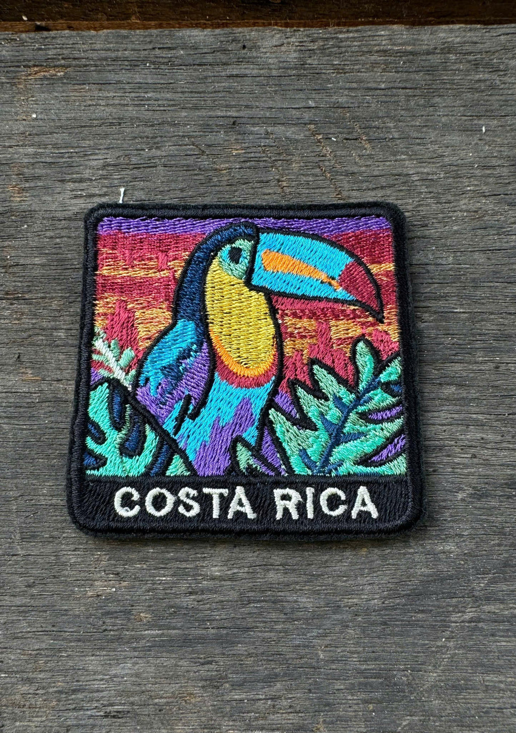 Colorful patch of a toucan with 'Costa Rica' text on a wooden surface