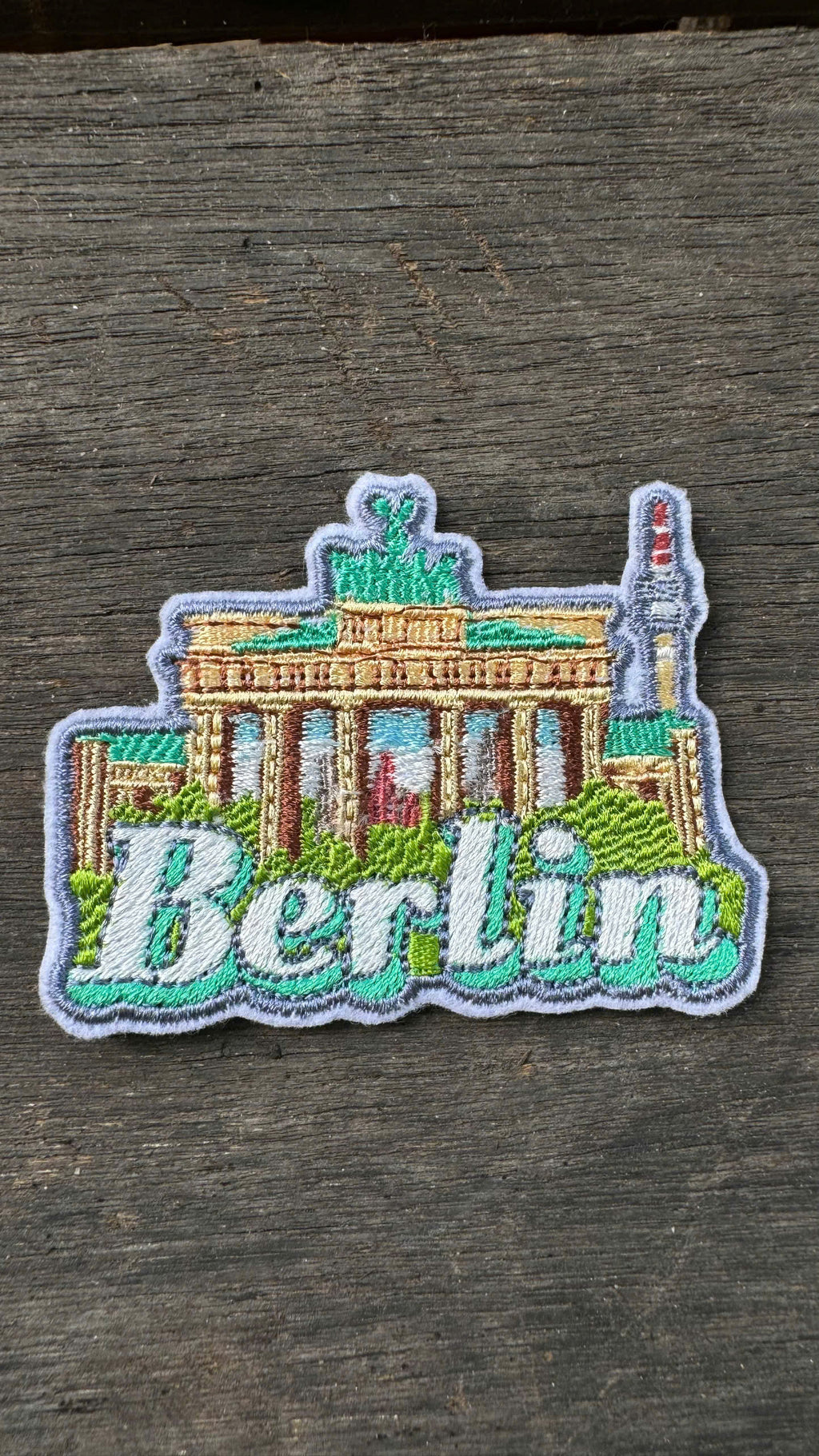Embroidered patch of the Brandenburg Gate with 'Berlin' text on a wooden surface